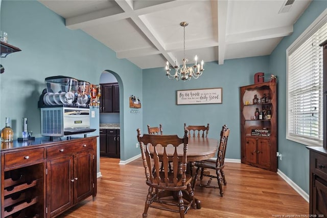dining space with light wood finished floors, arched walkways, a chandelier, coffered ceiling, and beamed ceiling