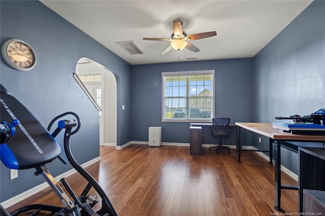 office area featuring a ceiling fan, wood finished floors, arched walkways, and baseboards