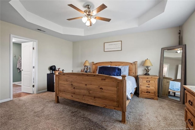 bedroom with a tray ceiling, carpet flooring, baseboards, and a ceiling fan