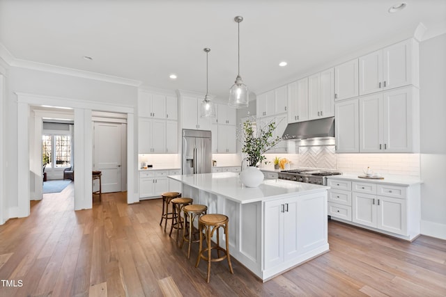 7212 Summer Tanager Trl, Raleigh, NC 27614 - kitchen featuring appliances with stainless steel finishes, under cabinet range hood, white cabinetry, a breakfast bar, and recessed lighting