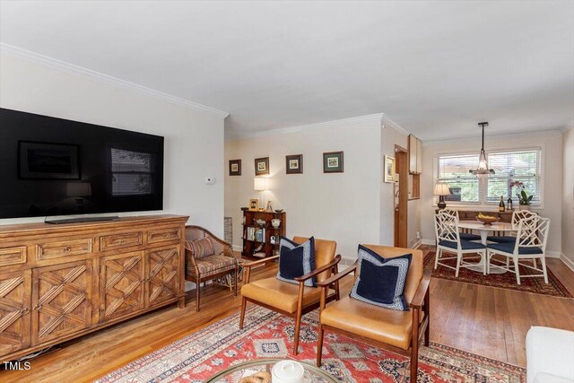 2913 Anderson Dr, Raleigh, NC 27608 - living room featuring light wood-style floors, ornamental molding, baseboards, and a chandelier