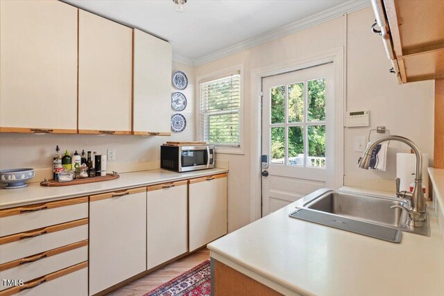2913 Anderson Dr, Raleigh, NC 27608 - kitchen with a sink, stainless steel microwave, light countertops, ornamental molding, and white cabinets