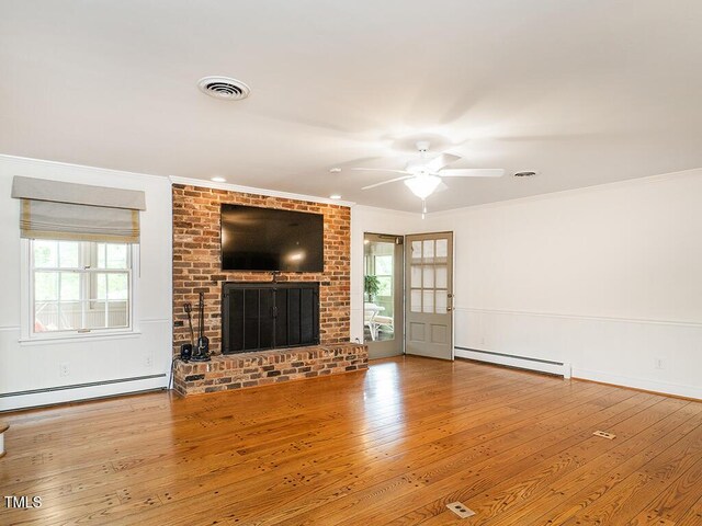 2228 Walker Ave, Burlington, NC 27215 - unfurnished living room with a baseboard heating unit, wood-type flooring, crown molding, and plenty of natural light