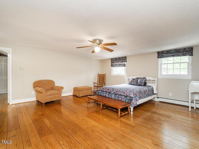 2228 Walker Ave, Burlington, NC 27215 - bedroom featuring a textured ceiling, light wood finished floors, a baseboard heating unit, a ceiling fan, and baseboards