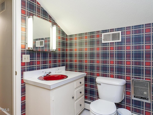 2228 Walker Ave, Burlington, NC 27215 - half bathroom with tile walls, toilet, vaulted ceiling, vanity, and a baseboard heating unit