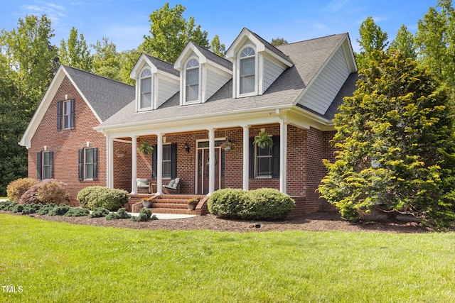 200 Daniel Ridge Ln, Roxboro, NC 27574 - cape cod house featuring covered porch, brick siding, a front yard, and a shingled roof