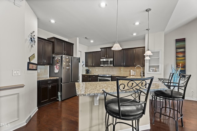 4612 Hanging Fern Ln, Raleigh, NC 27604 - kitchen with appliances with stainless steel finishes, a kitchen bar, dark brown cabinets, decorative backsplash, and recessed lighting