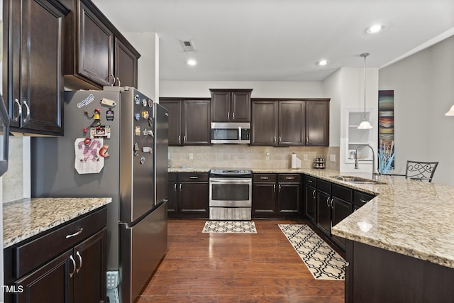 4612 Hanging Fern Ln, Raleigh, NC 27604 - kitchen with appliances with stainless steel finishes, a sink, dark wood finished floors, dark brown cabinets, and light stone countertops