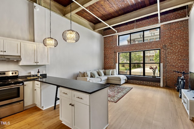 kitchen with stainless steel electric range oven, brick wall, wood ceiling, a high ceiling, and under cabinet range hood