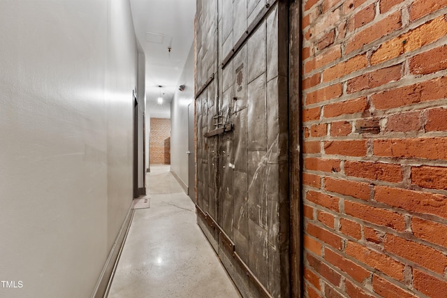 hallway featuring baseboards and concrete floors