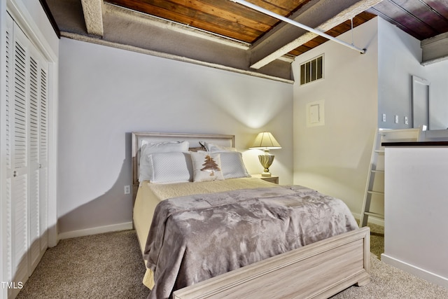 carpeted bedroom with beamed ceiling, wood ceiling, baseboards, and a closet