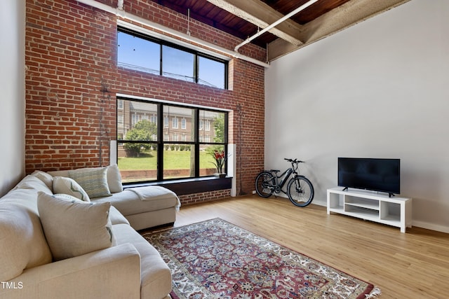 living room with wooden ceiling, wood finished floors, brick wall, beamed ceiling, and baseboards