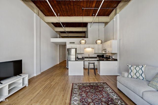 living room featuring wood ceiling, a towering ceiling, light wood finished floors, and baseboards