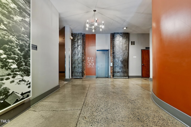 hallway featuring speckle patterned floor, elevator, and baseboards