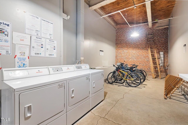 shared laundry room with brick wall, washing machine and clothes dryer, and wooden ceiling