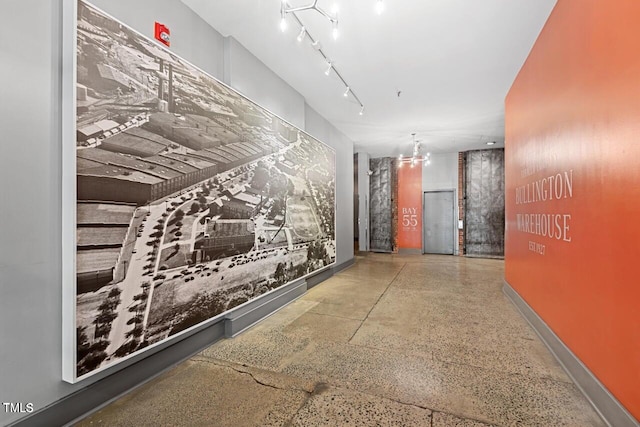 hall featuring speckle patterned floor and baseboards