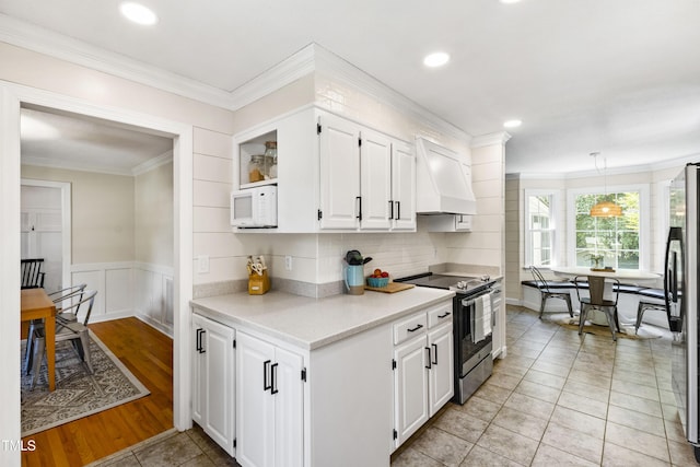 5413 Lower Creek Ct, Apex, NC 27539 - kitchen with stainless steel range with electric stovetop, premium range hood, white microwave, crown molding, and light countertops