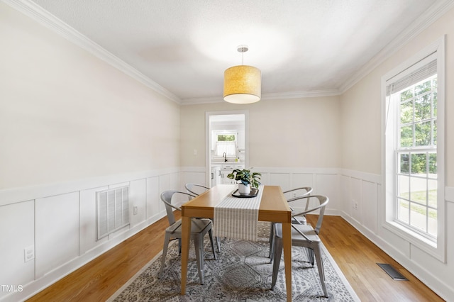 5413 Lower Creek Ct, Apex, NC 27539 - dining room featuring healthy amount of natural light, light wood-type flooring, ornamental molding, and a wainscoted wall