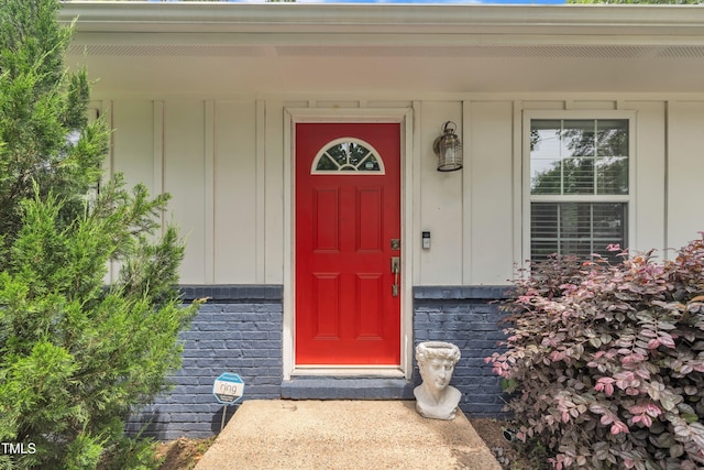 doorway to property with board and batten siding, brick siding, and covered porch