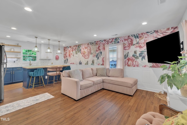 living area with wallpapered walls, wainscoting, light wood finished floors, and recessed lighting
