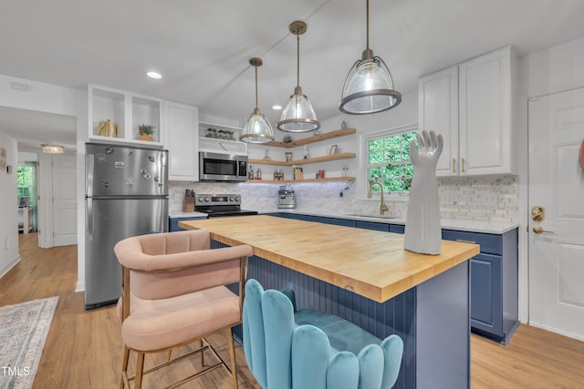kitchen with open shelves, stainless steel appliances, wood counters, a sink, and blue cabinets