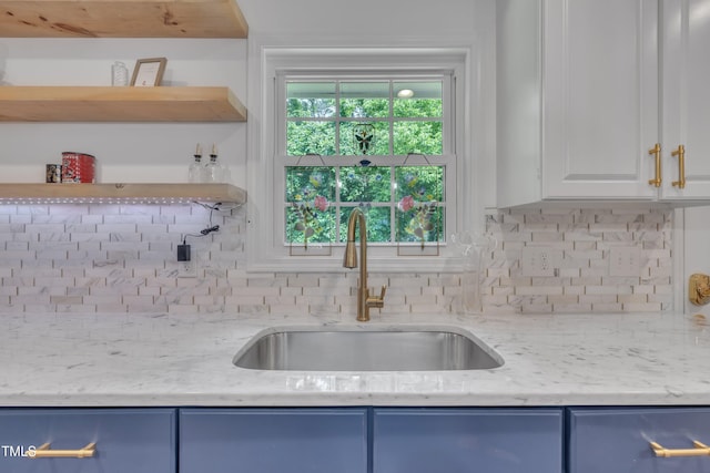 kitchen with open shelves, a sink, and blue cabinetry