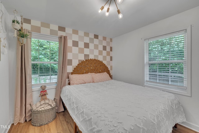 bedroom featuring wood finished floors, a chandelier, and baseboards