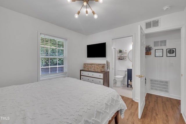 bedroom with light wood finished floors, baseboards, a chandelier, and ensuite bathroom