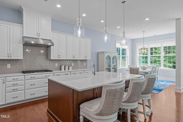 2511 Range Overlook Xing, Apex, NC 27523 - kitchen with dark wood finished floors, white cabinets, backsplash, under cabinet range hood, and a center island with sink