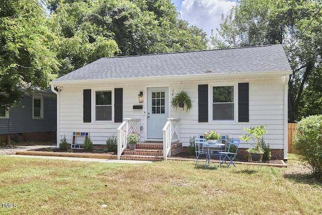 bungalow with a front yard and a shingled roof