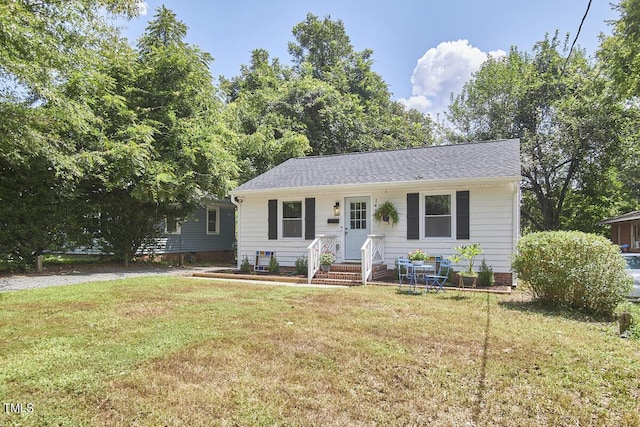 view of front of house featuring a front lawn and a shingled roof