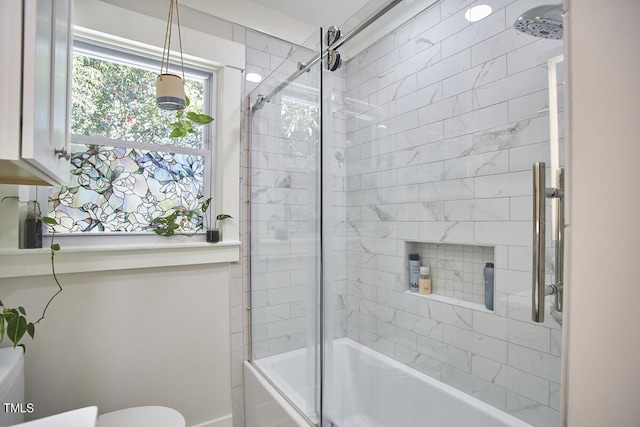 bathroom featuring toilet and bath / shower combo with glass door