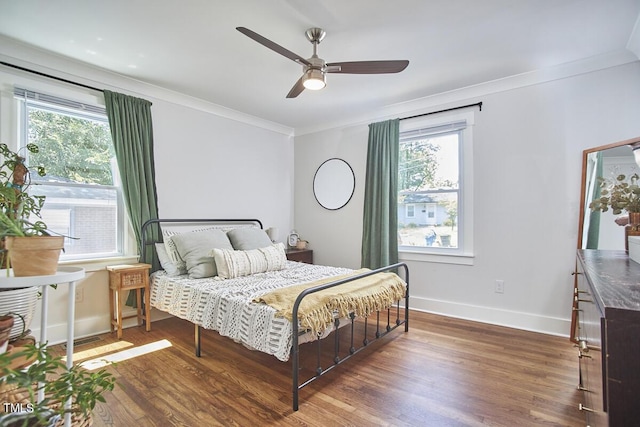 bedroom featuring wood finished floors, crown molding, baseboards, and a ceiling fan