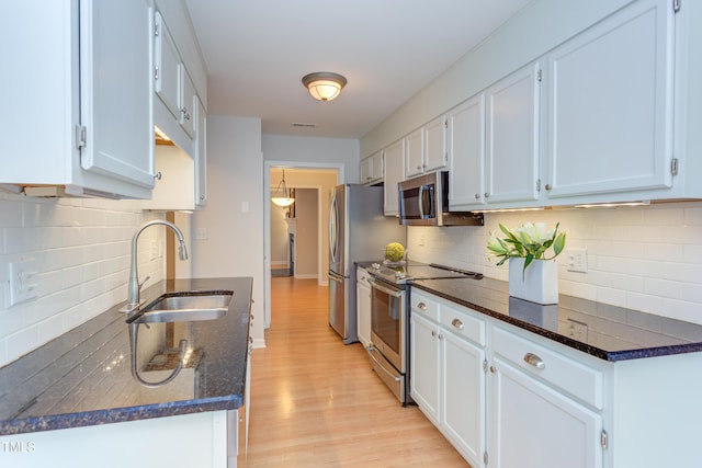 2222 Pathway Dr, Chapel Hill, NC 27516 - kitchen featuring appliances with stainless steel finishes, decorative backsplash, light wood-style floors, dark stone counters, and white cabinets