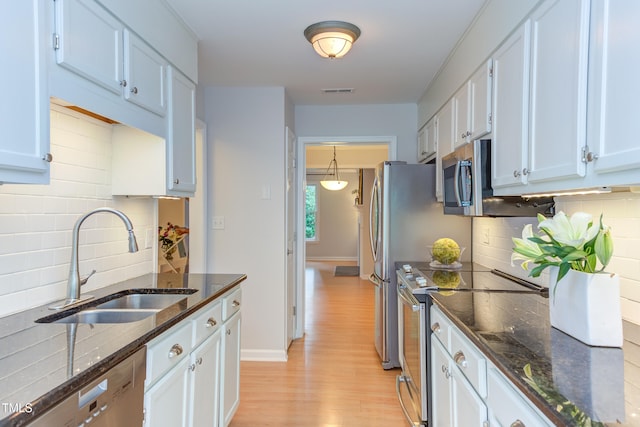 2222 Pathway Dr, Chapel Hill, NC 27516 - kitchen with stainless steel appliances, light wood-style flooring, backsplash, dark stone counters, and white cabinetry