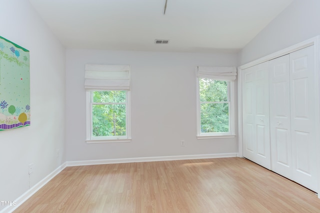 2222 Pathway Dr, Chapel Hill, NC 27516 - unfurnished bedroom with light wood finished floors, multiple windows, and a closet
