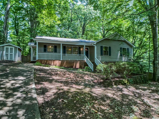 1104 Theresa Ct, Raleigh, NC 27615 - ranch-style home featuring covered porch, a storage unit, an outbuilding, driveway, and view of wooded area