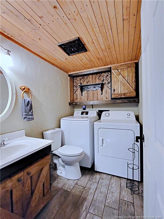 6261 Stoney Point Loop, Fayetteville, NC 28306 - half bathroom with washer and dryer, wood ceiling, toilet, wood finished floors, and a sink