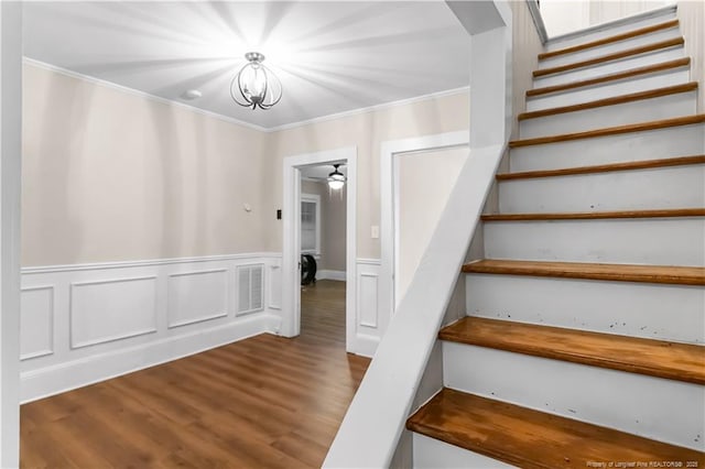 1001 N Orange Ave, Dunn, NC 28334 - staircase with wood finished floors, a chandelier, a wainscoted wall, and crown molding