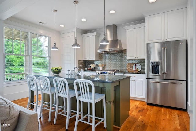 253 Tobacco Farm Way, Chapel Hill, NC 27516 - kitchen featuring stainless steel refrigerator with ice dispenser, wall chimney range hood, plenty of natural light, an island with sink, and recessed lighting