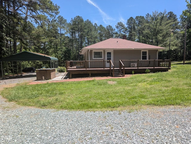 rear view of property with a carport, a lawn, a wooden deck, and view of scattered trees