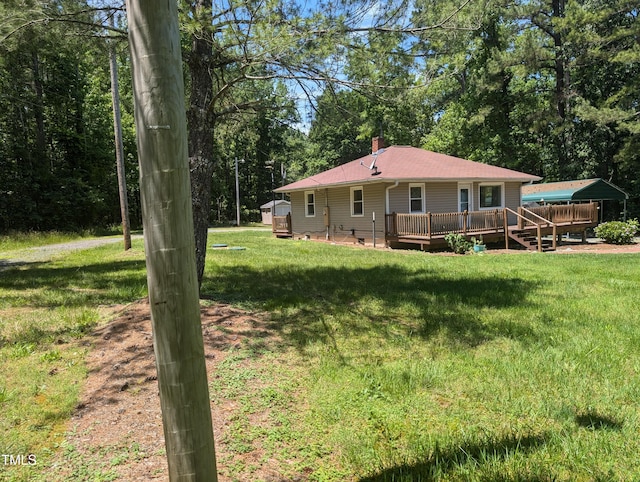 rear view of property featuring a wooden deck, a yard, and a chimney