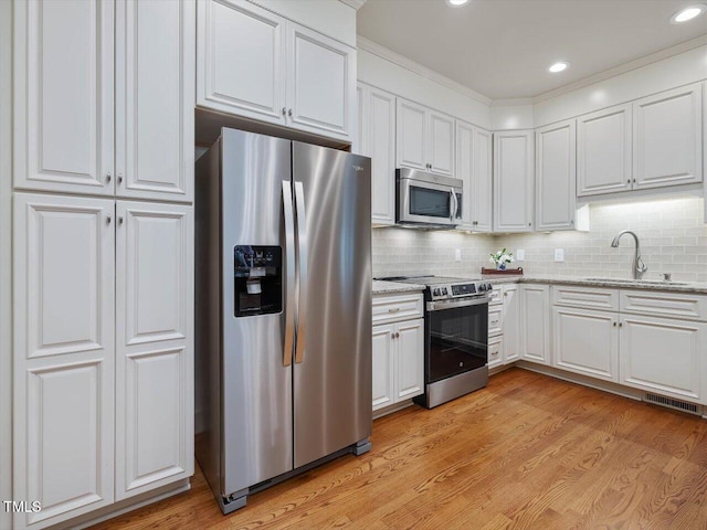 3347 Ridgecrest Ct, Raleigh, NC 27607 - kitchen with stainless steel appliances, a sink, white cabinetry, light wood-type flooring, and light stone counters