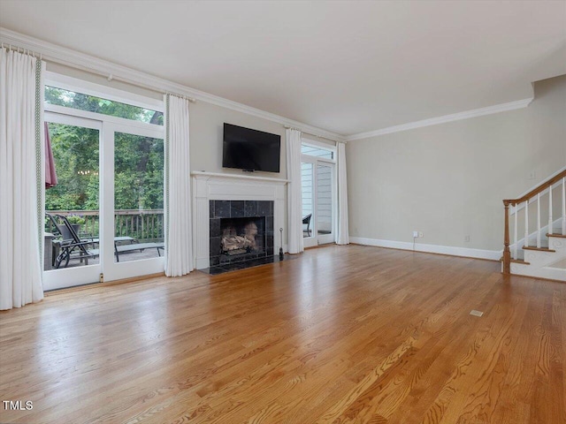 3347 Ridgecrest Ct, Raleigh, NC 27607 - unfurnished living room with ornamental molding, stairs, a tile fireplace, light wood-style floors, and baseboards