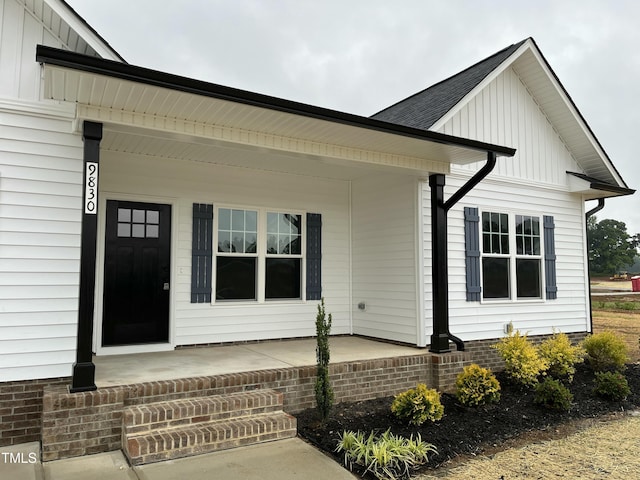 property entrance with a porch, board and batten siding, and roof with shingles