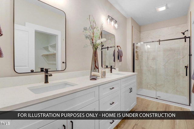 full bathroom with wood finished floors, a shower stall, and double vanity