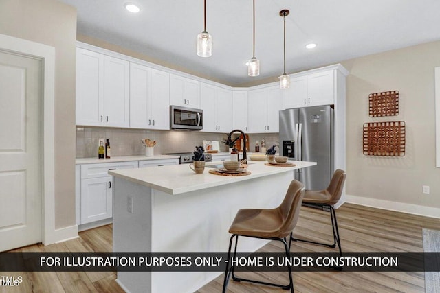 kitchen with stainless steel appliances, light wood finished floors, a kitchen breakfast bar, white cabinets, and recessed lighting