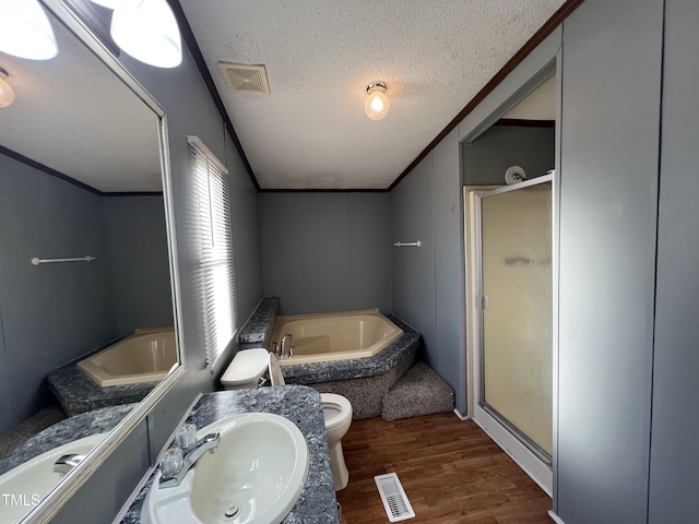 bathroom featuring a shower stall, wood finished floors, toilet, a textured ceiling, and a garden tub