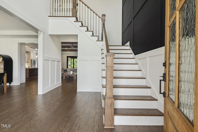1141 Duke Farm Dr, Wake Forest, NC 27587 - stairs with a decorative wall, wood finished floors, a towering ceiling, and a wainscoted wall