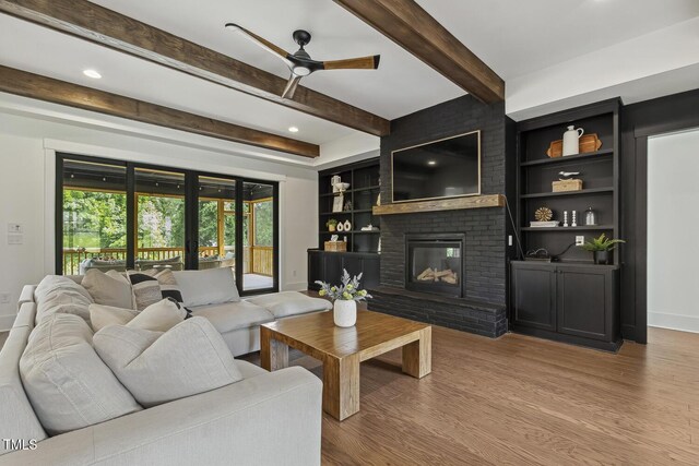 1141 Duke Farm Dr, Wake Forest, NC 27587 - living area with ceiling fan, wood finished floors, baseboards, a brick fireplace, and beam ceiling